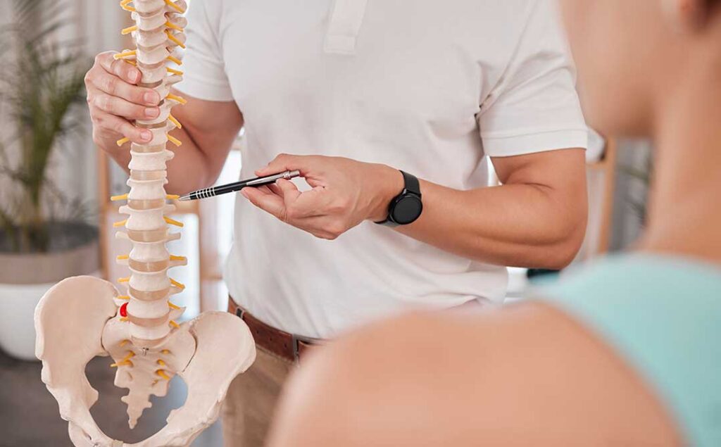 A chiropractor checks the posture of an adult patient during a wellness session in a comfortable clinic setting.